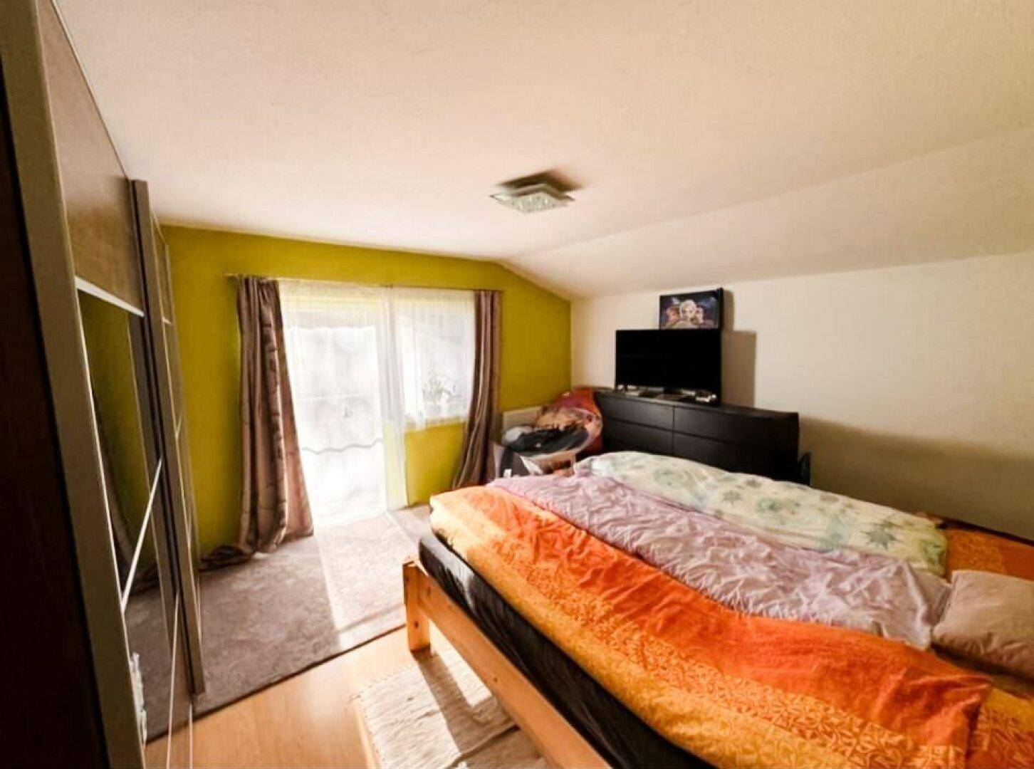 Schlafzimmer mit Doppelbett, Kleiderschrank und Zugang zu einem Balkon.