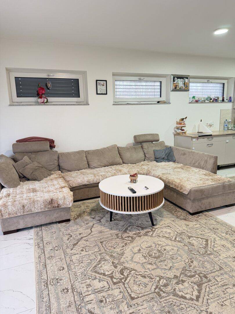 Gemütliches Wohnzimmer mit großem Ecksofa, modernem Couchtisch und viel Tageslicht.