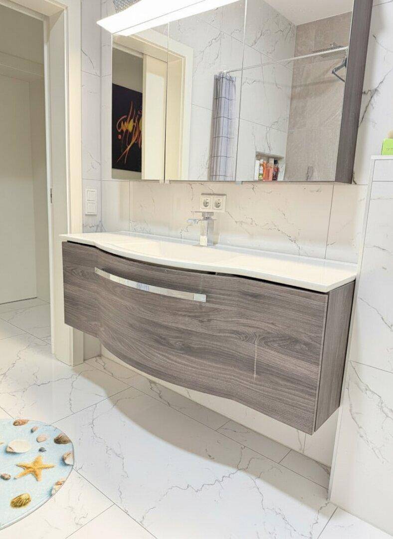 Elegantes Badezimmer mit modernem Waschtischunterschrank, Einzelwaschbecken und Spiegelschrank.