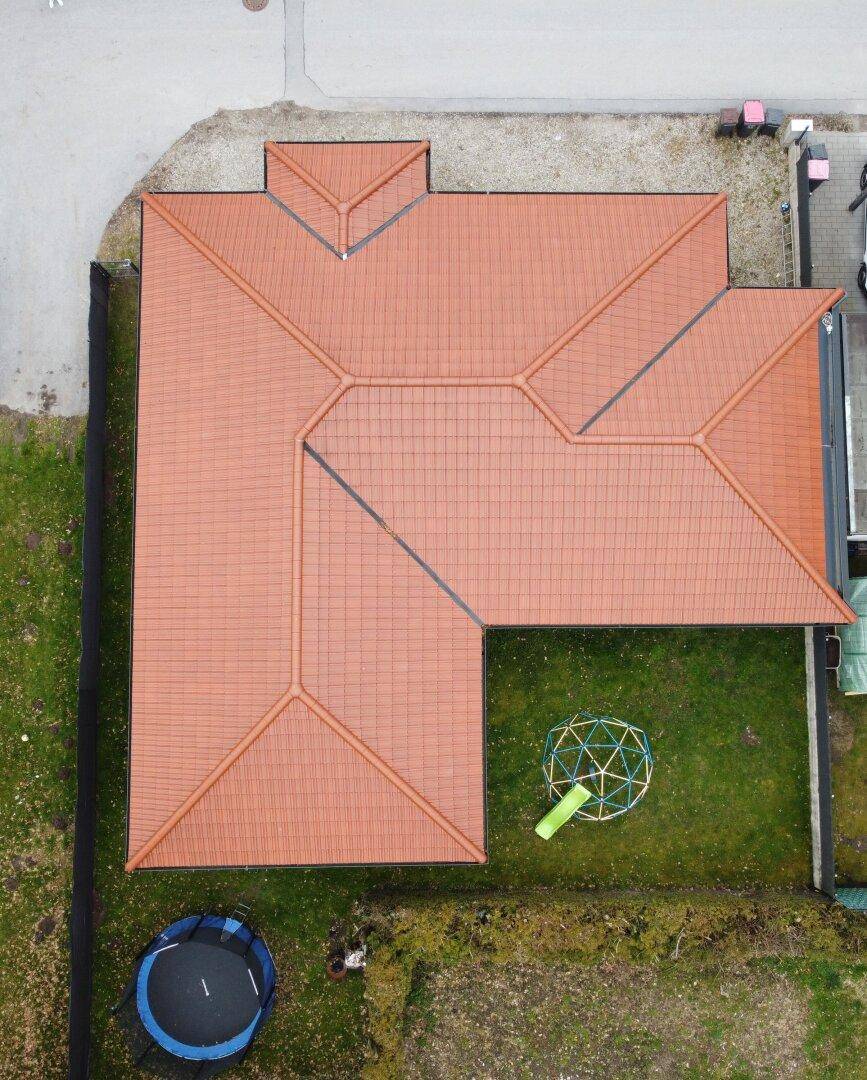 Luftaufnahme des Hauses mit Ziegeldach, Garten und Spielgeräten.
