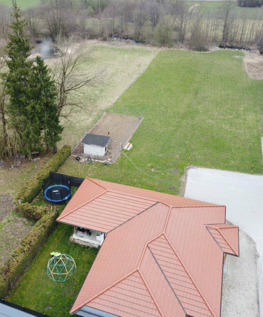 Weitläufige Luftaufnahme des Anwesens mit Haus, Garten und angrenzenden Grünflächen.
