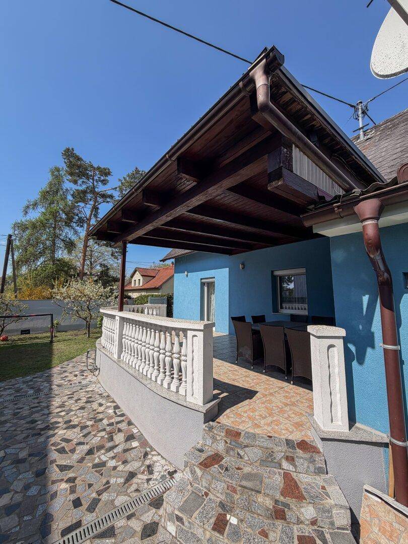 Überdachte Terrasse mit Sitzgelegenheiten und gefliestem Boden, ideal für Mahlzeiten im Freien.