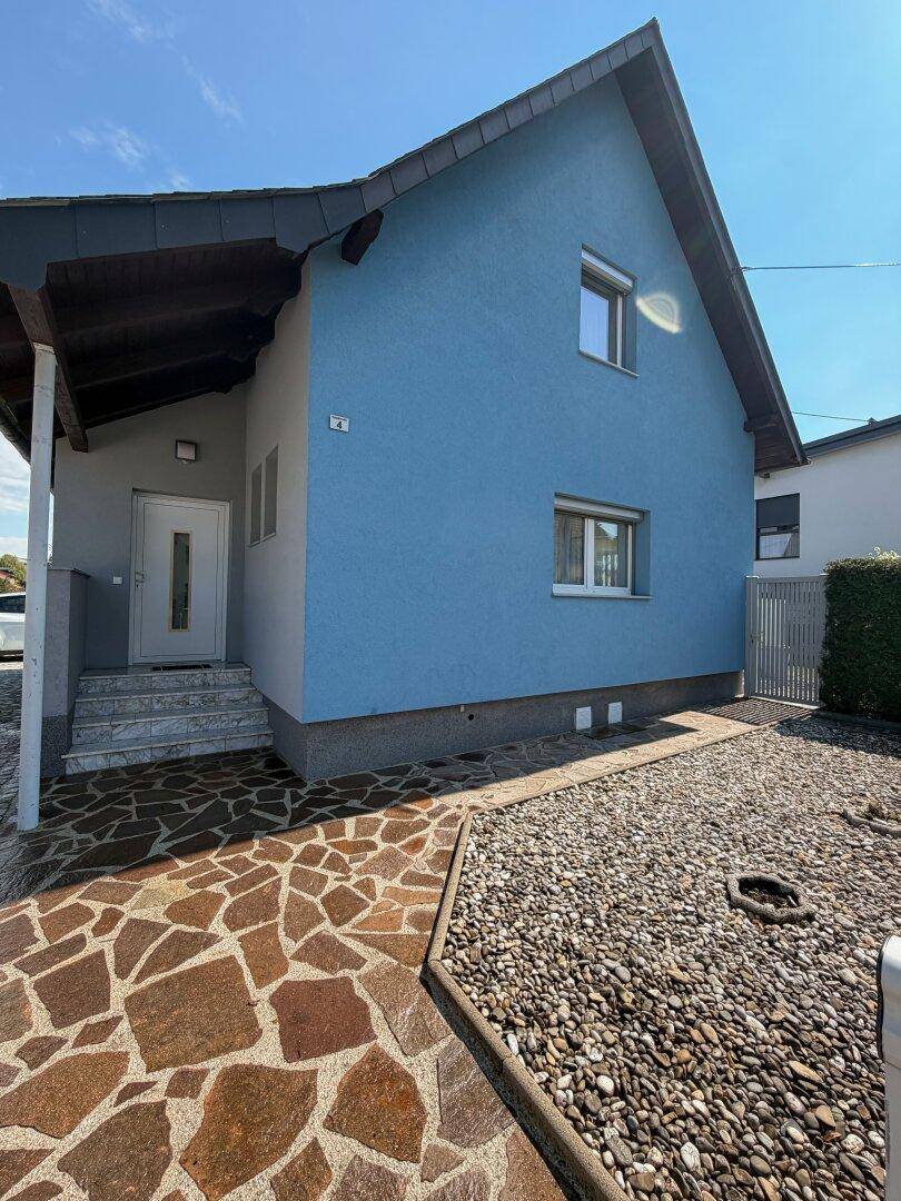 Vorderansicht des Hauses mit blauer Fassade, Steintreppe und Kiesbeet im Vorgarten.