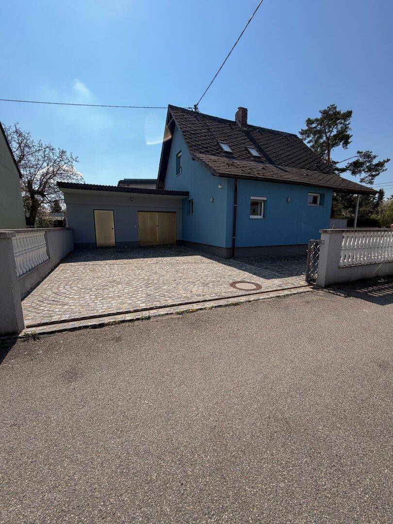 Seitenansicht des Hauses mit Zufahrt, Garage und gepflegtem Außenbereich.
