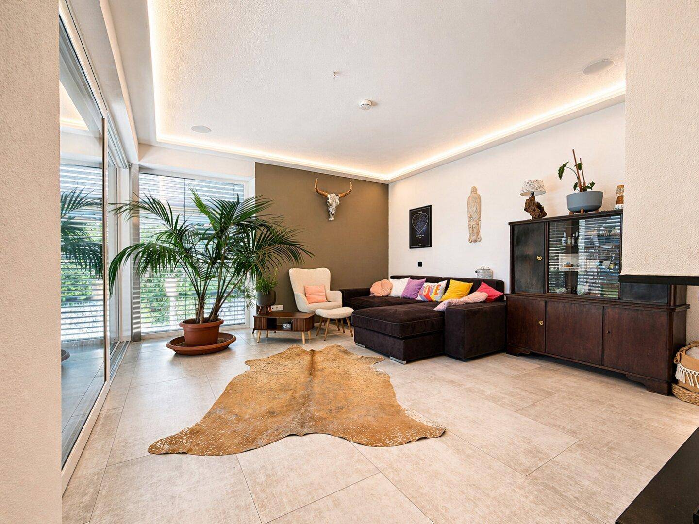 Geräumiges Wohnzimmer mit großem Sofa, Fliesenboden und Zugang zur Terrasse.
