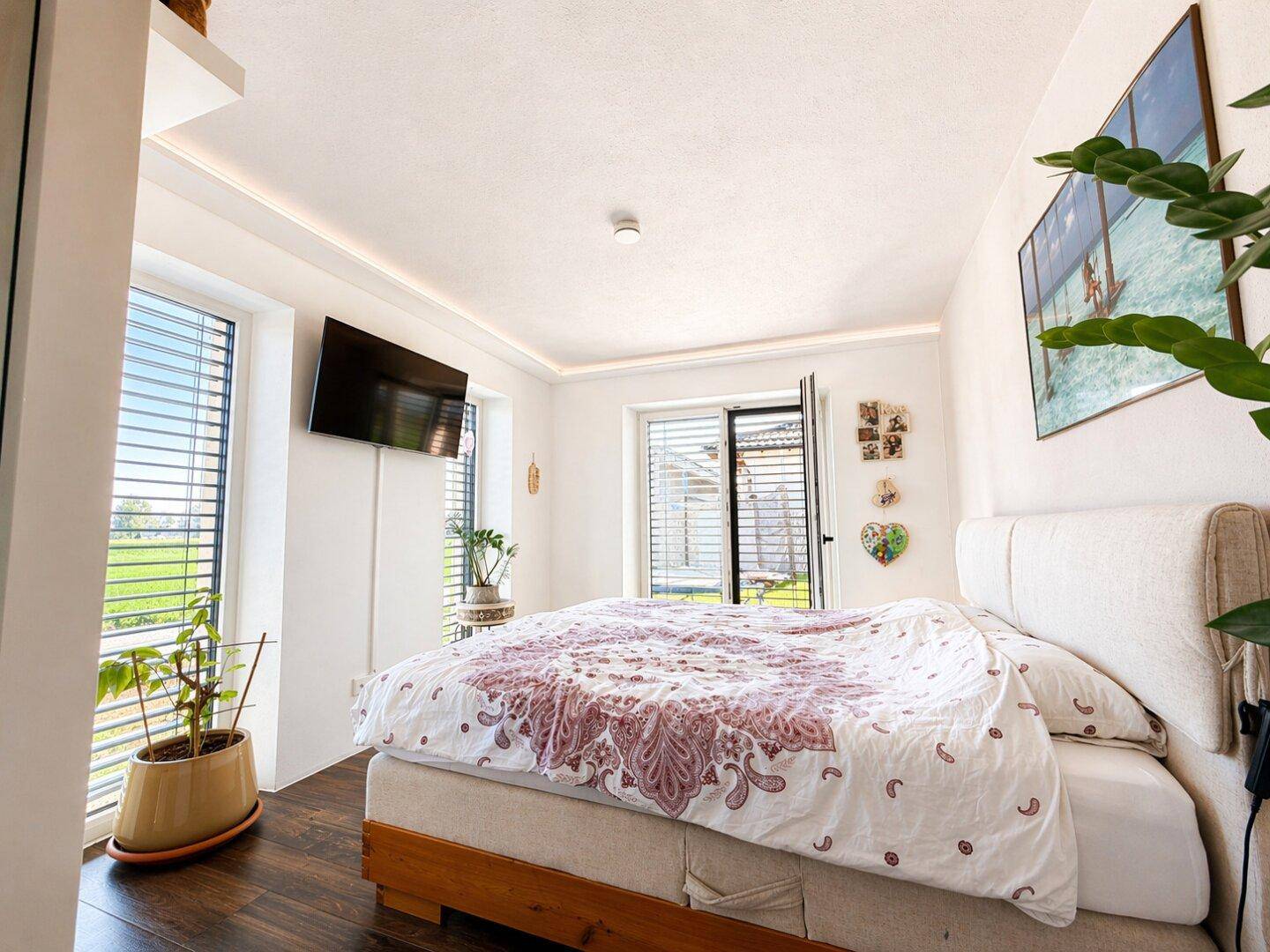 Schlafzimmer mit großem Bett, Blick ins Grüne und viel Tageslicht.