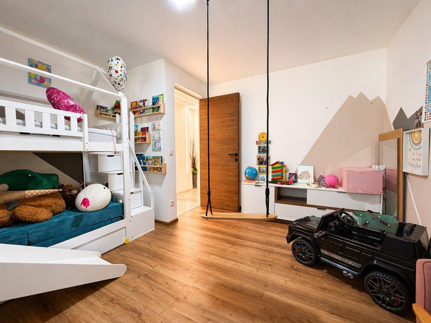 Gemütliches Kinderzimmer mit Etagenbett, Schaukel und Spielzeug.