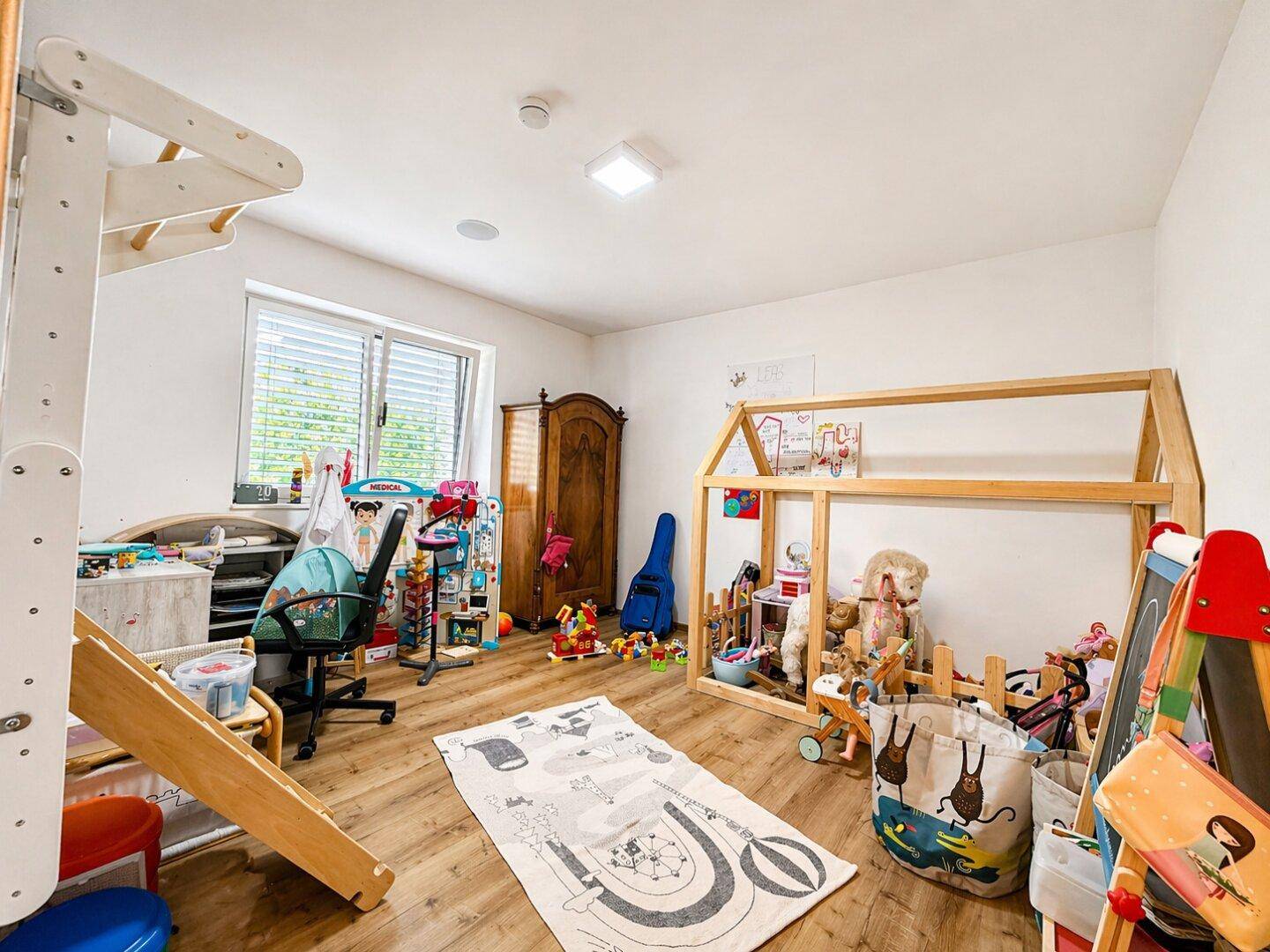 Helles Kinderzimmer mit Spielhaus-Bett, Holzboden und viel Platz zum Spielen.