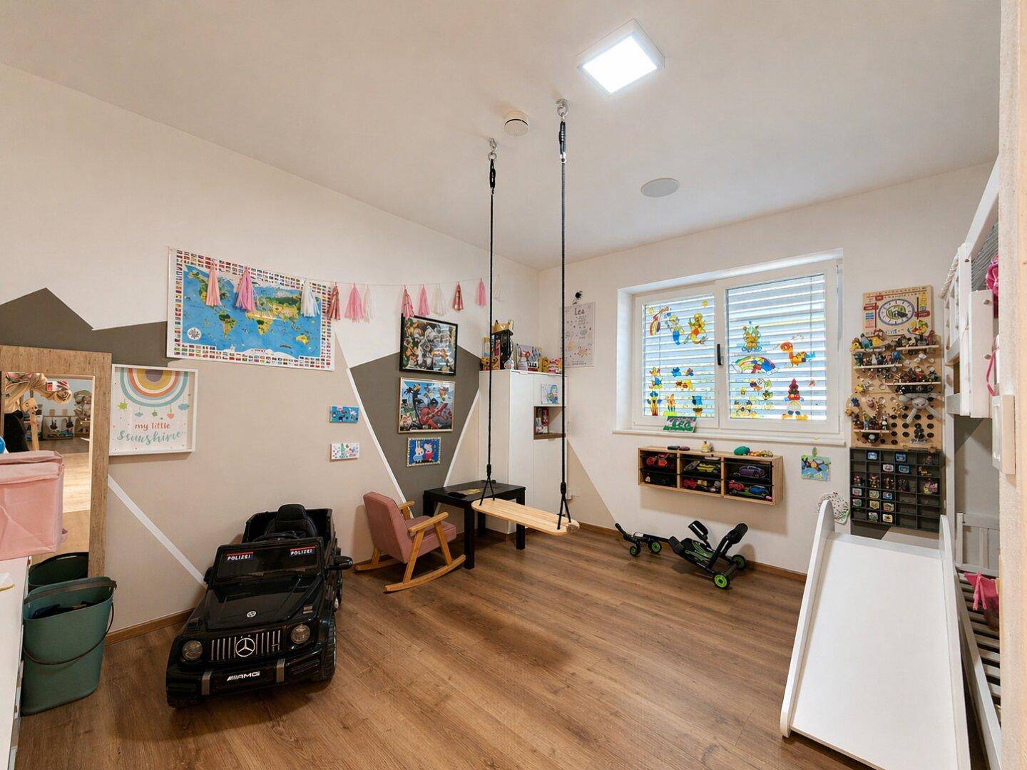 Farbenfrohes Kinderzimmer mit Spielgeräten, Schaukel und hellem Laminatboden.