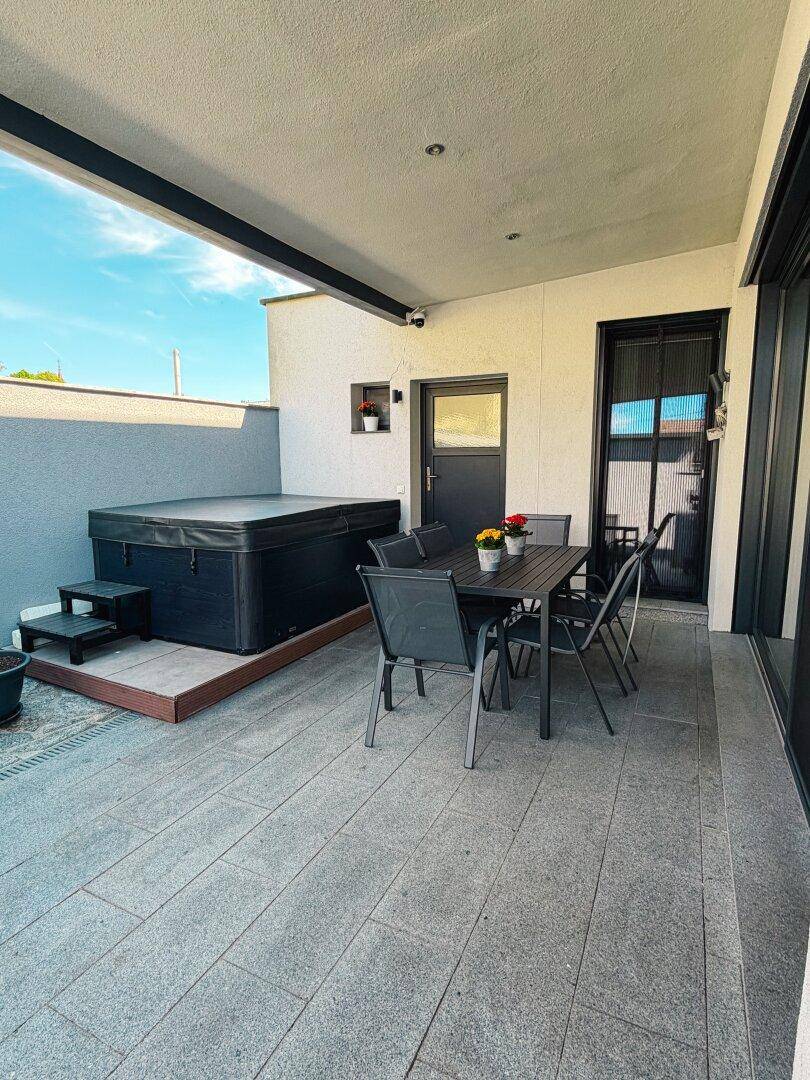 Überdachte Terrasse mit Whirlpool und Essbereich im Freien, ideal zum Entspannen.