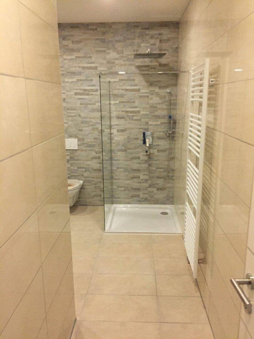 Modernes Badezimmer mit begehbarer Dusche, Wand-WC und beheiztem Handtuchhalter.