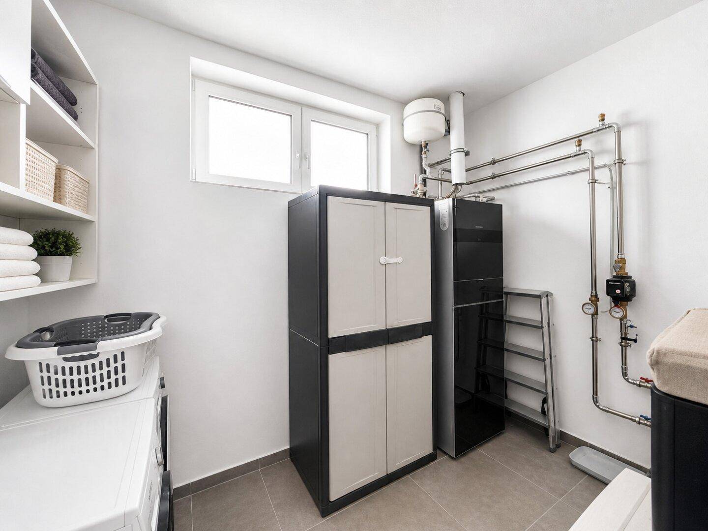 Praktischer Hauswirtschaftsraum mit Waschmaschine, Trockner und Heizungsanlage.