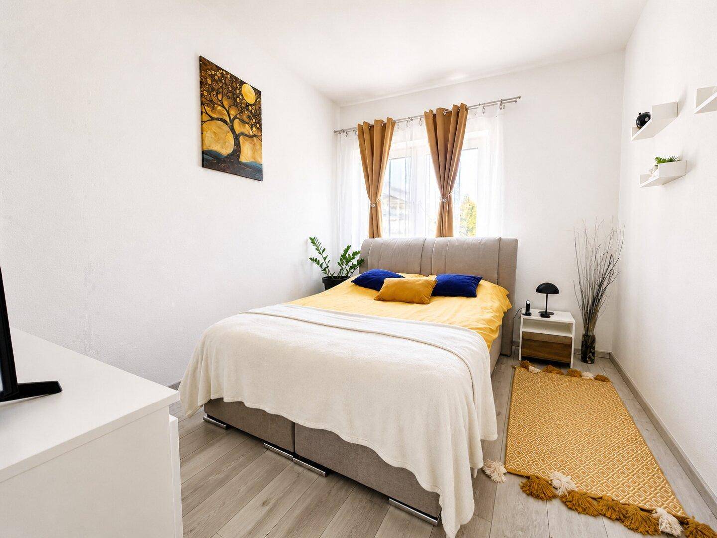 Gemütliches Schlafzimmer mit Doppelbett, Nachttisch und einem farbenfrohen Bild an der Wand.