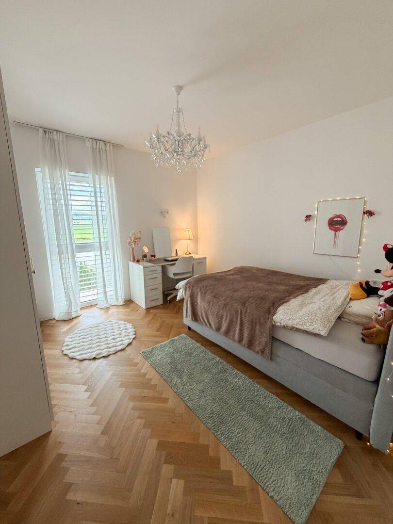 Helles Kinderzimmer mit Bett, Schreibtisch und elegantem Kronleuchter für eine angenehme Atmosphäre.