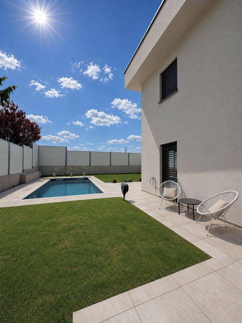 Moderne Hausfassade mit Garten, Poolbereich und stilvollen Sitzgelegenheiten im Freien.