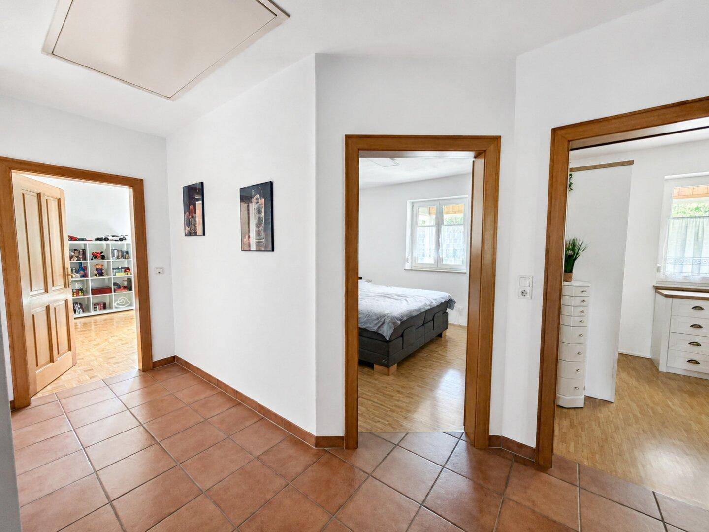 Heller Flur mit Terrakotta-Fliesenboden und Holztüren, der zu verschiedenen Räumen führt.