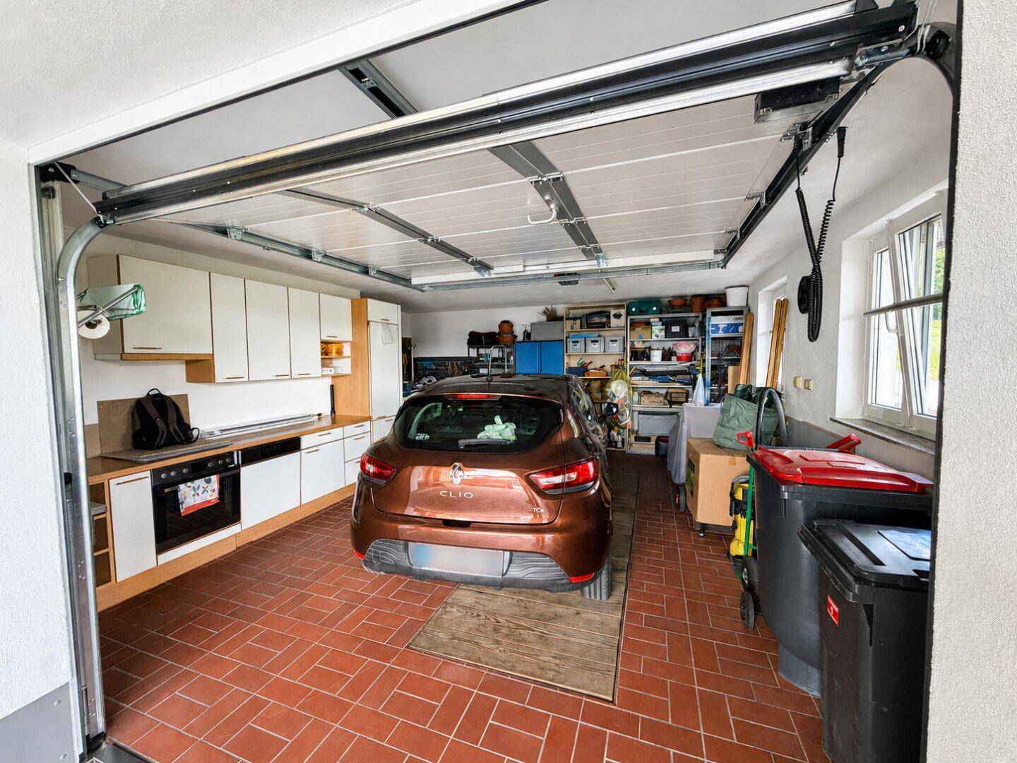 Geräumige Garage mit Fliesenboden, Stauraum und einer integrierten Küchenzeile.