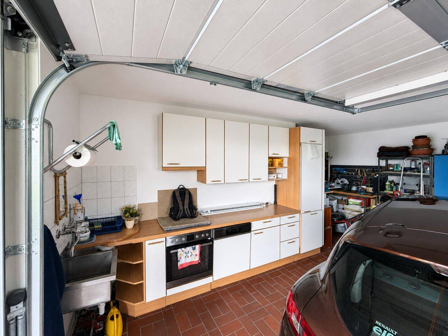 Garage mit integrierter Küchenzeile, Backofen und Stauraum, genutzt als Werkstatt.