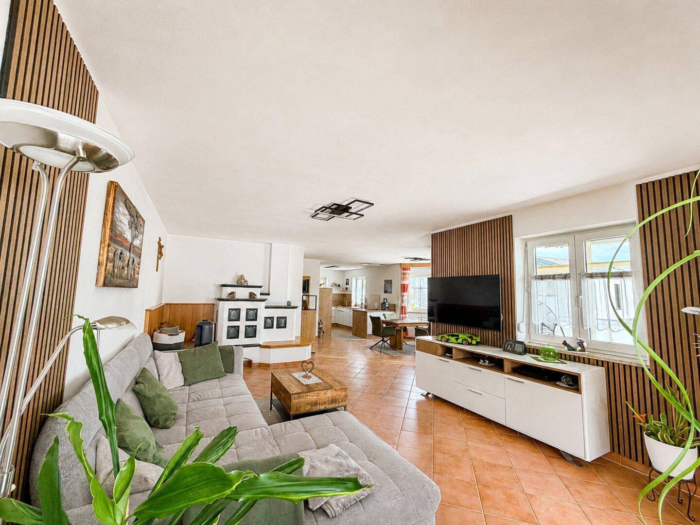 Helles Wohnzimmer mit Terrakotta-Fliesenboden, modernem Sofa und Holzakzenten an den Wänden.