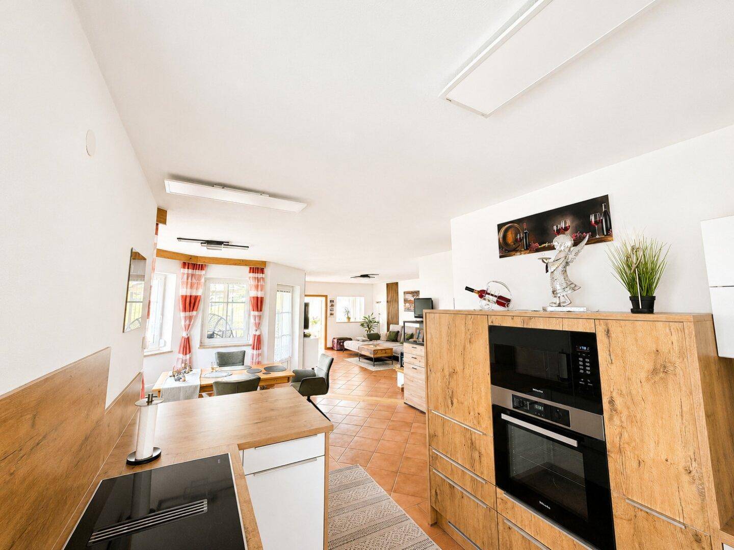 Offener Wohn- und Essbereich mit Terrakottafliesen und Blick in die moderne Küche.