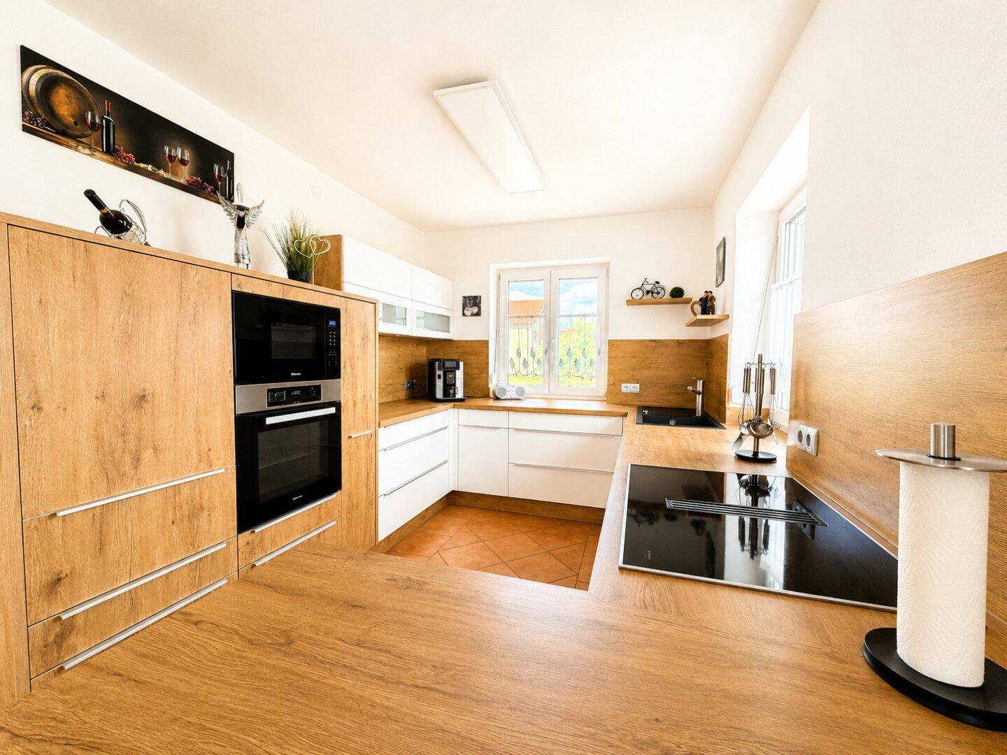 Moderne Küche mit Holz- und weißen Fronten, integrierten Geräten und Induktionskochfeld.