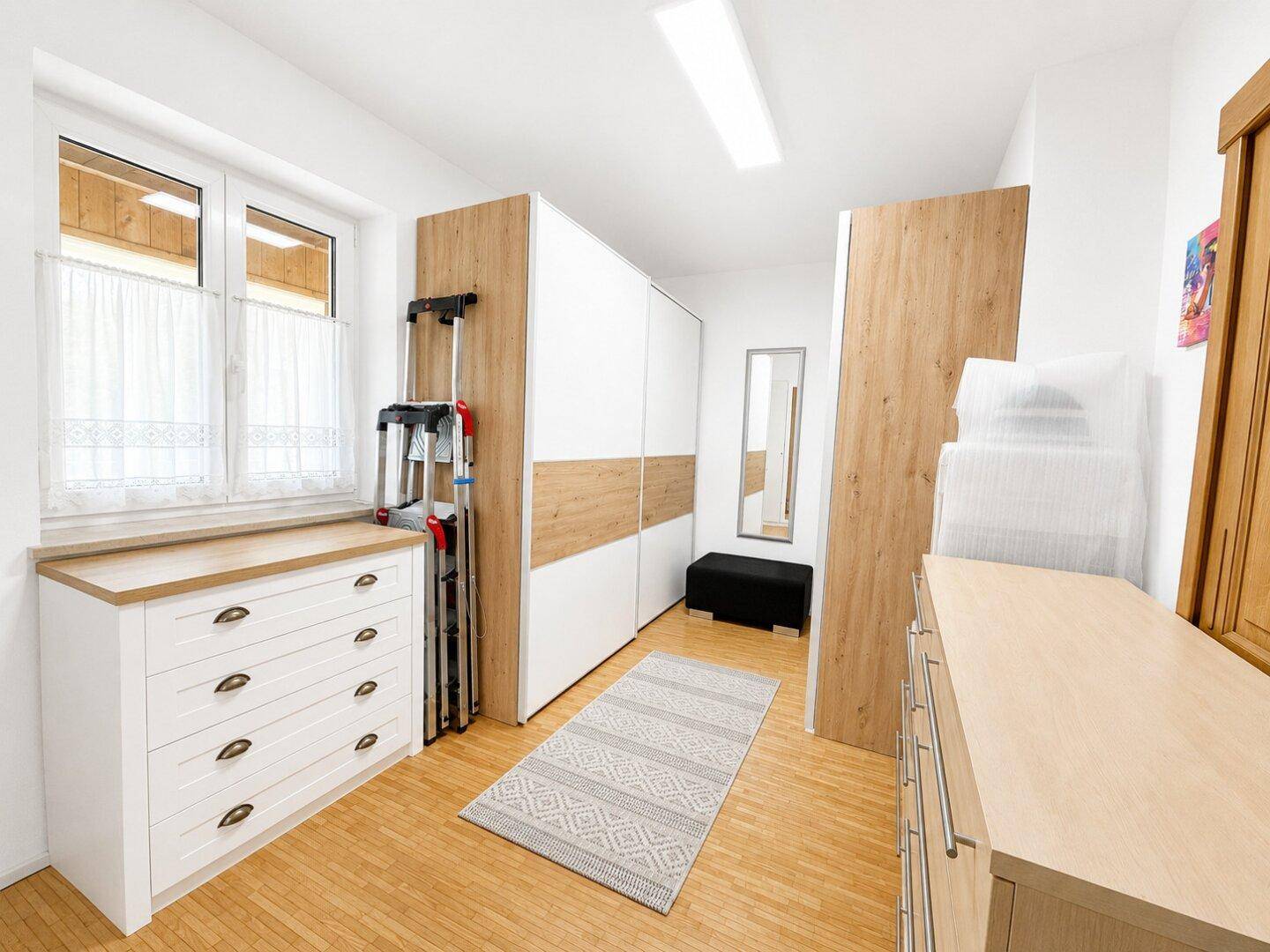 Heller Flur mit Einbauschränken, Kommode und Fenster für Tageslicht.
