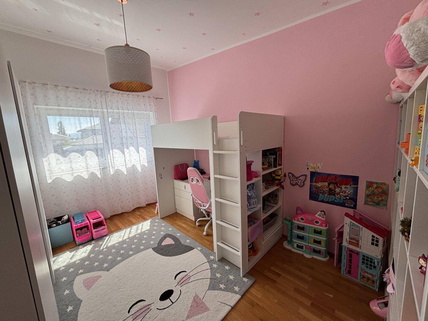 Farbenfrohes Kinderzimmer mit Hochbett, Schreibtisch und rosa Wänden.