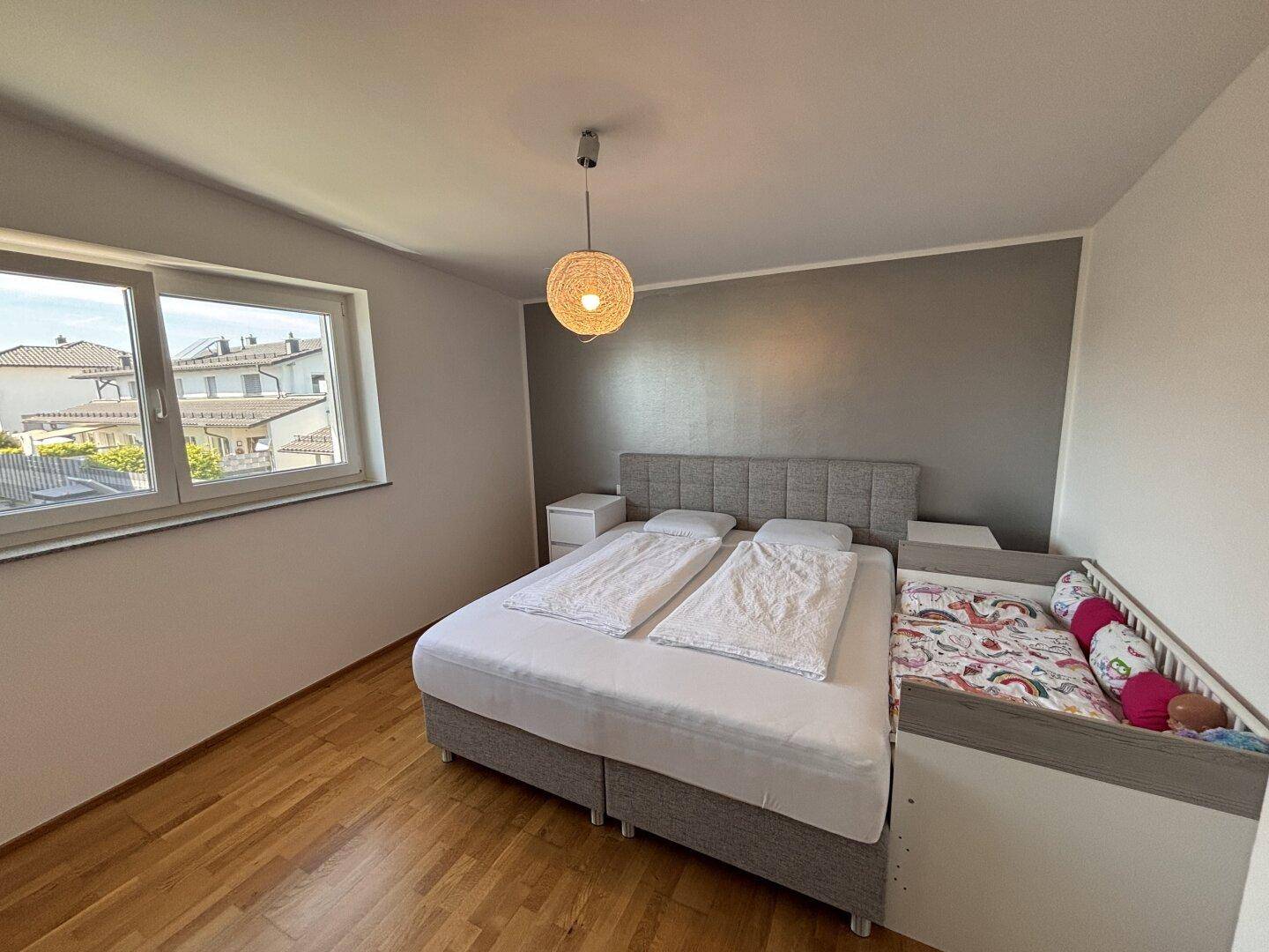 Gemütliches Schlafzimmer mit Doppelbett, Nachttischen und hellem Holzfußboden.