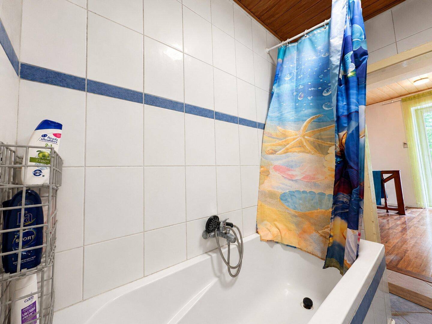 Badewanne mit Duschvorhang und weißen Fliesen im Badezimmer.