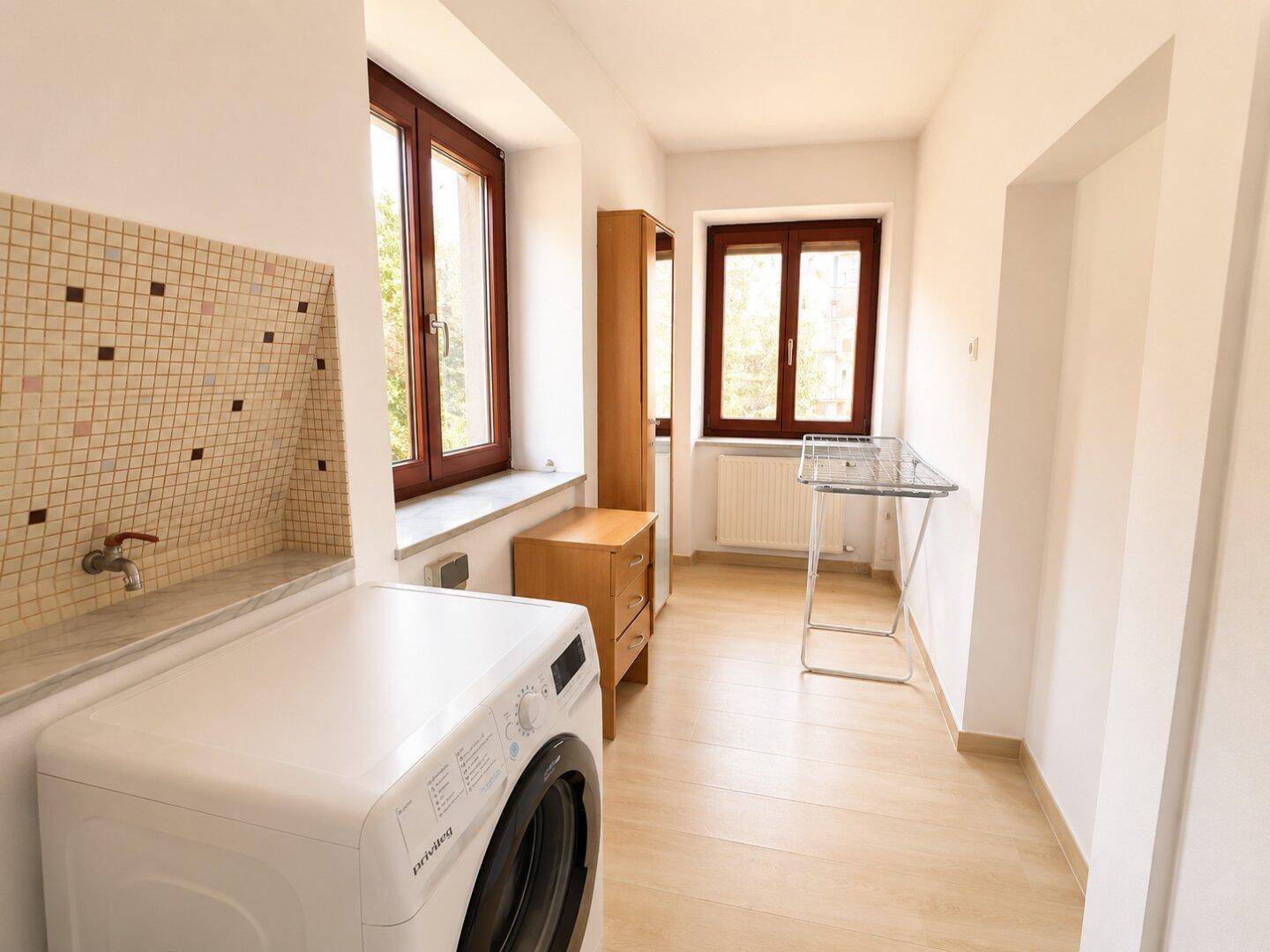 Hauswirtschaftsraum mit Waschmaschine, Fenster und Trockenständer.