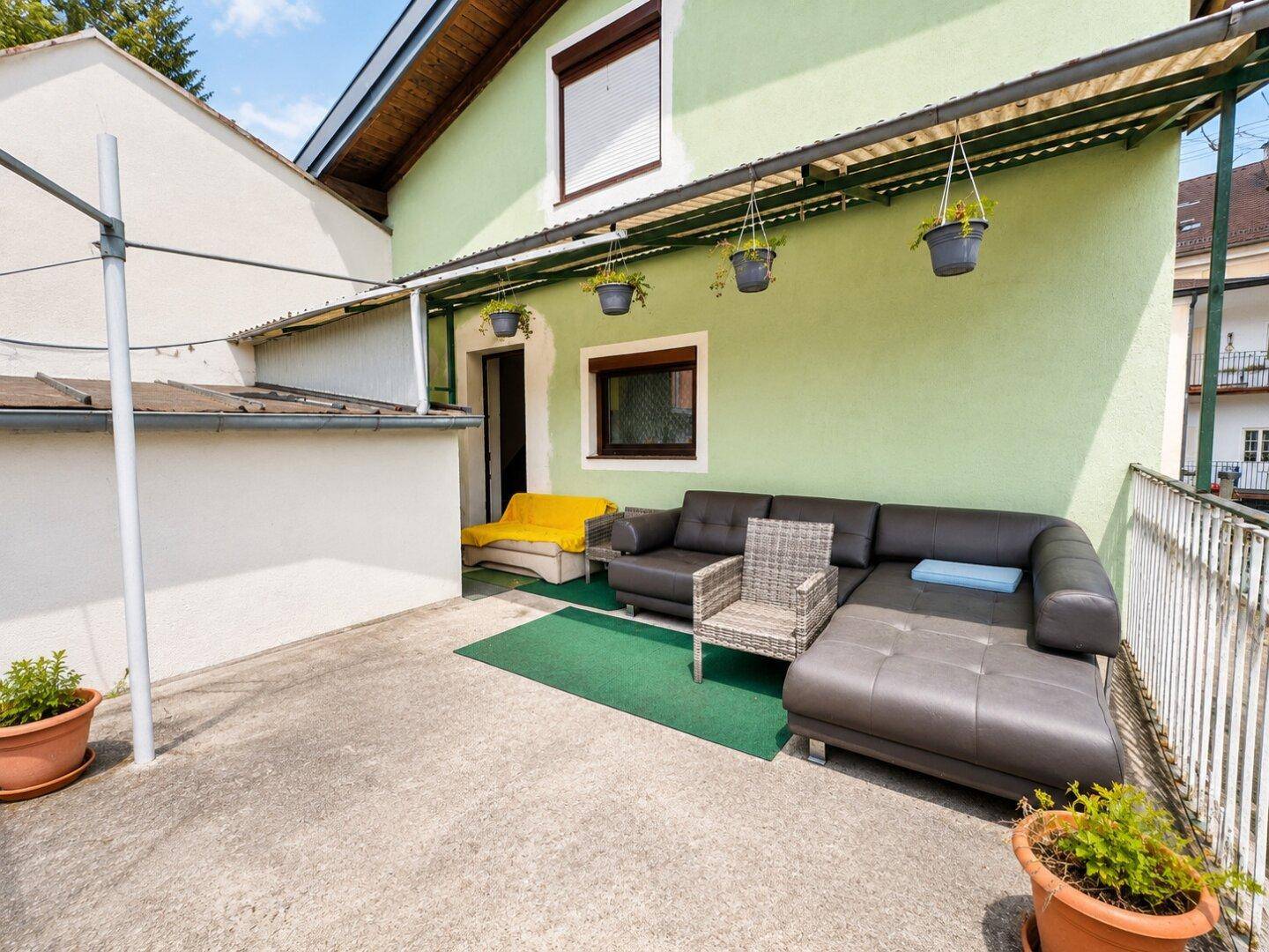 Überdachte Terrasse mit Sitzgelegenheiten und Blick auf die Umgebung.
