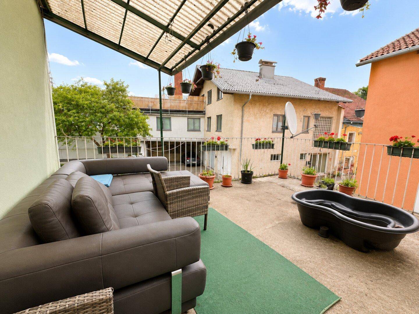 Große Terrasse mit Lounge-Sofa und Blick auf benachbarte Häuser.
