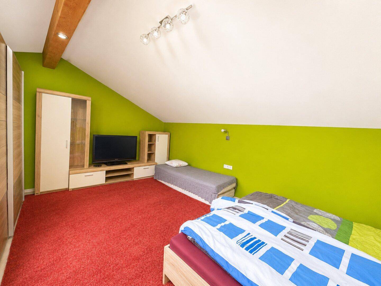 Dachschlafzimmer mit grünen Wänden, schrägen Decken und zwei Einzelbetten.
