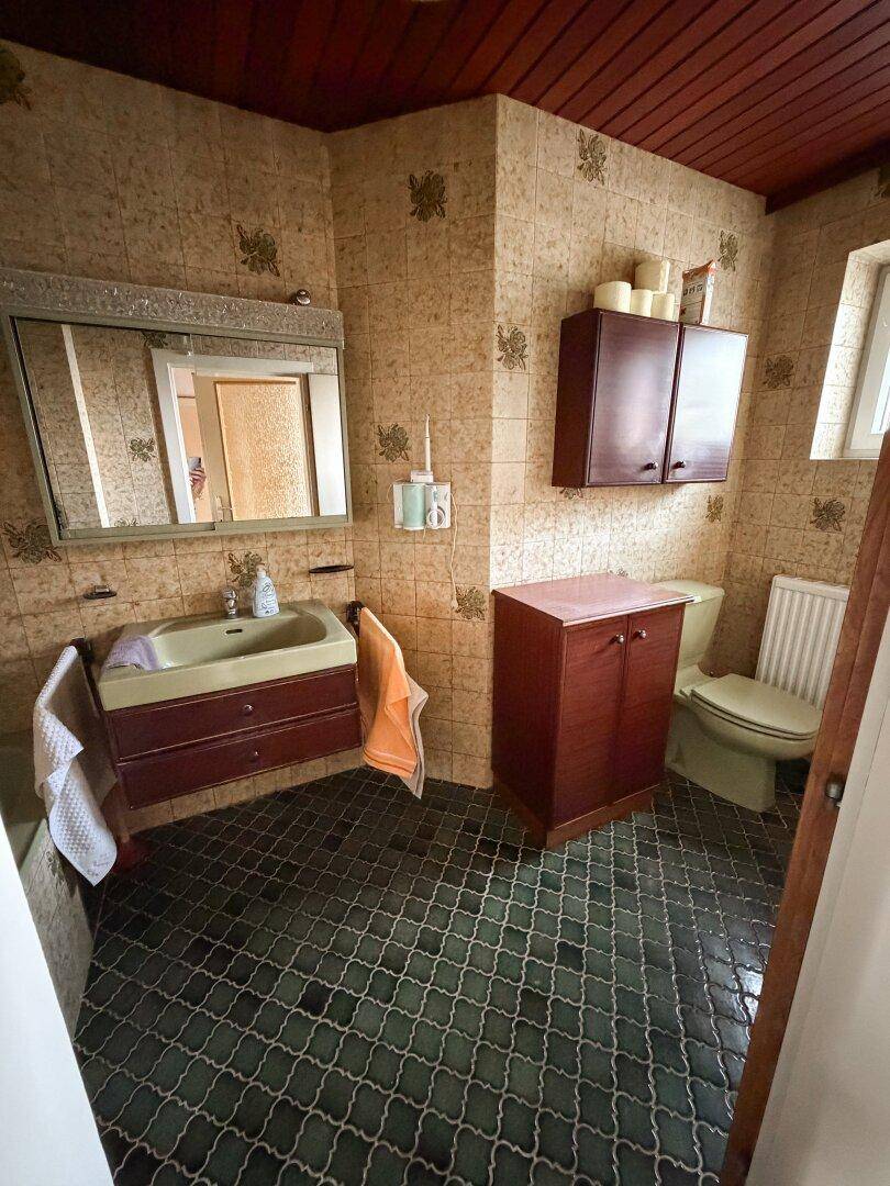 Badezimmer im Stil der 80er Jahre mit grünen Fliesen, passendem Waschbecken und Holzdecke.