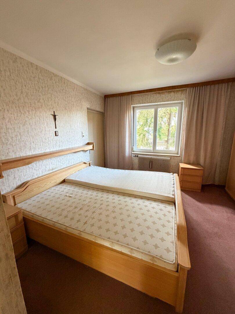 Schlafzimmer mit zwei Einzelbetten, Teppichboden und einem Fenster, das für natürliche Belüftung sorgt.
