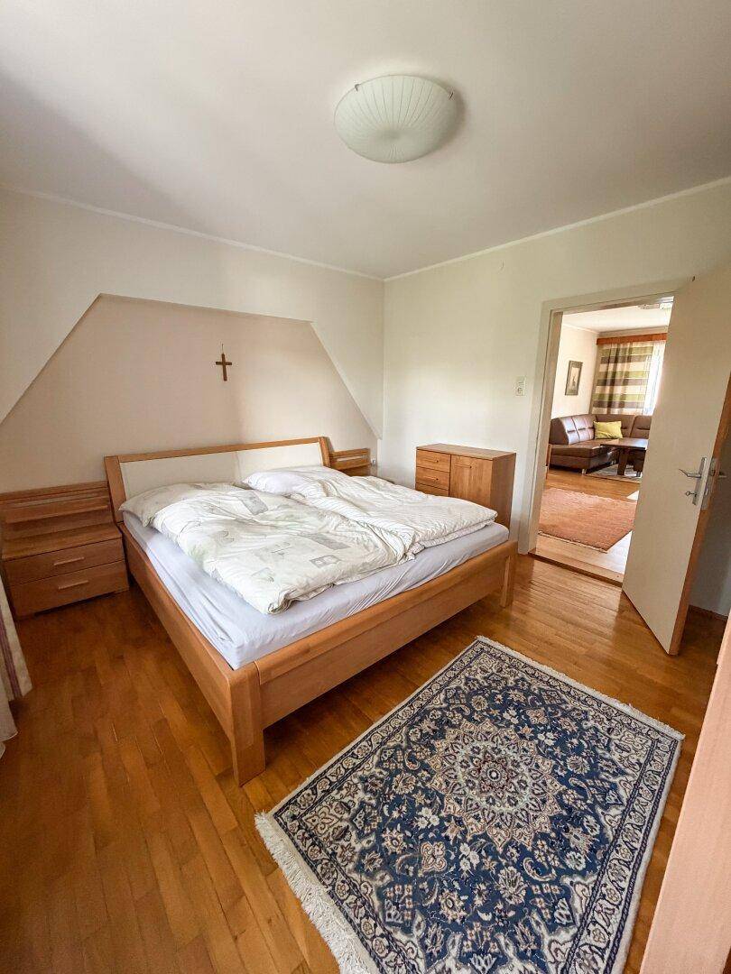 Gemütliches Schlafzimmer mit Doppelbett, Parkettboden und einem Teppich, der Wärme spendet.
