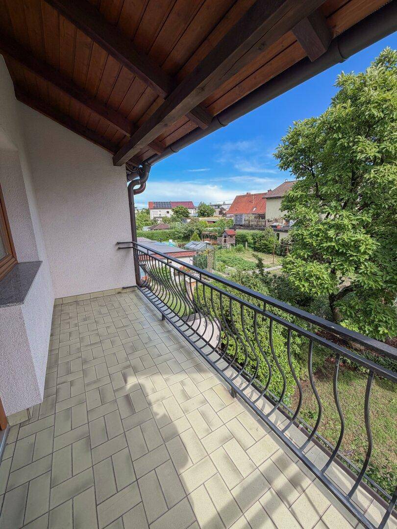 Balkon mit Fliesenboden und schmiedeeisernem Geländer, bietet einen weiten Blick über den Garten.