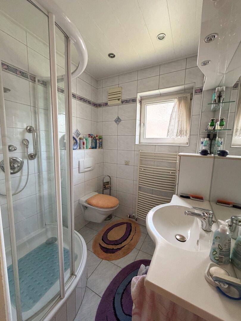 Helles Badezimmer mit Duschkabine, WC, Waschbecken und weißen Fliesen.
