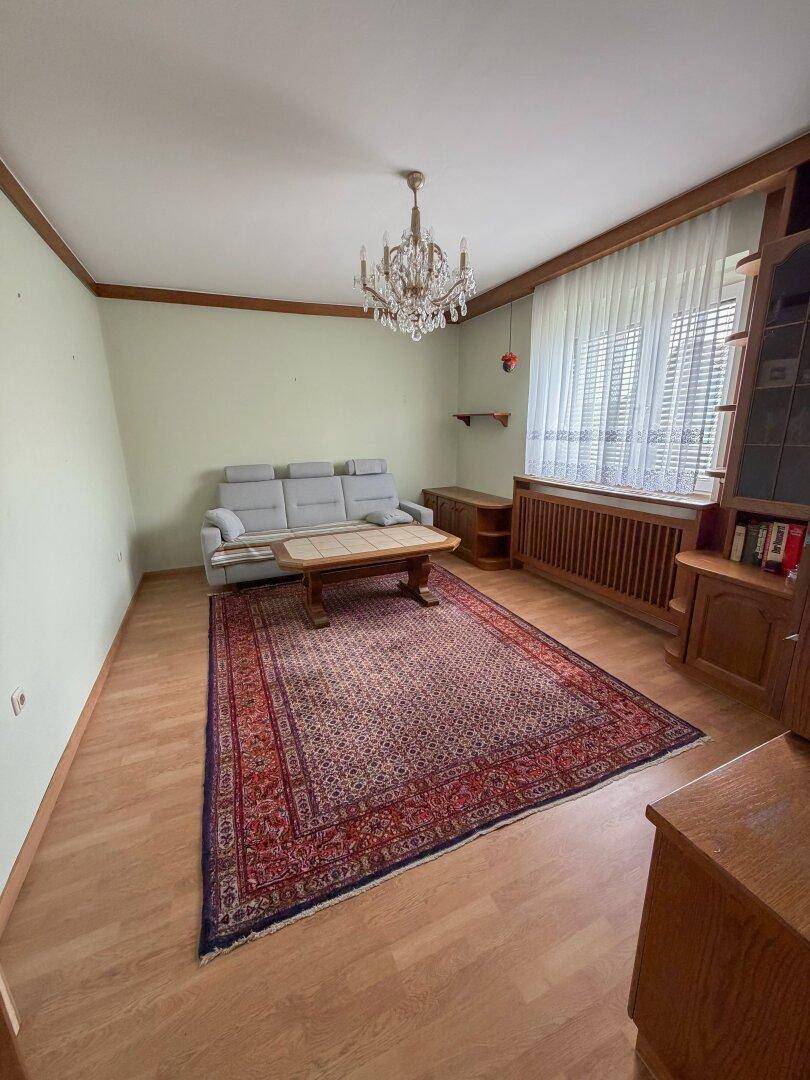 Geräumiges Wohnzimmer mit Holzboden, Sofa und einem Kronleuchter.