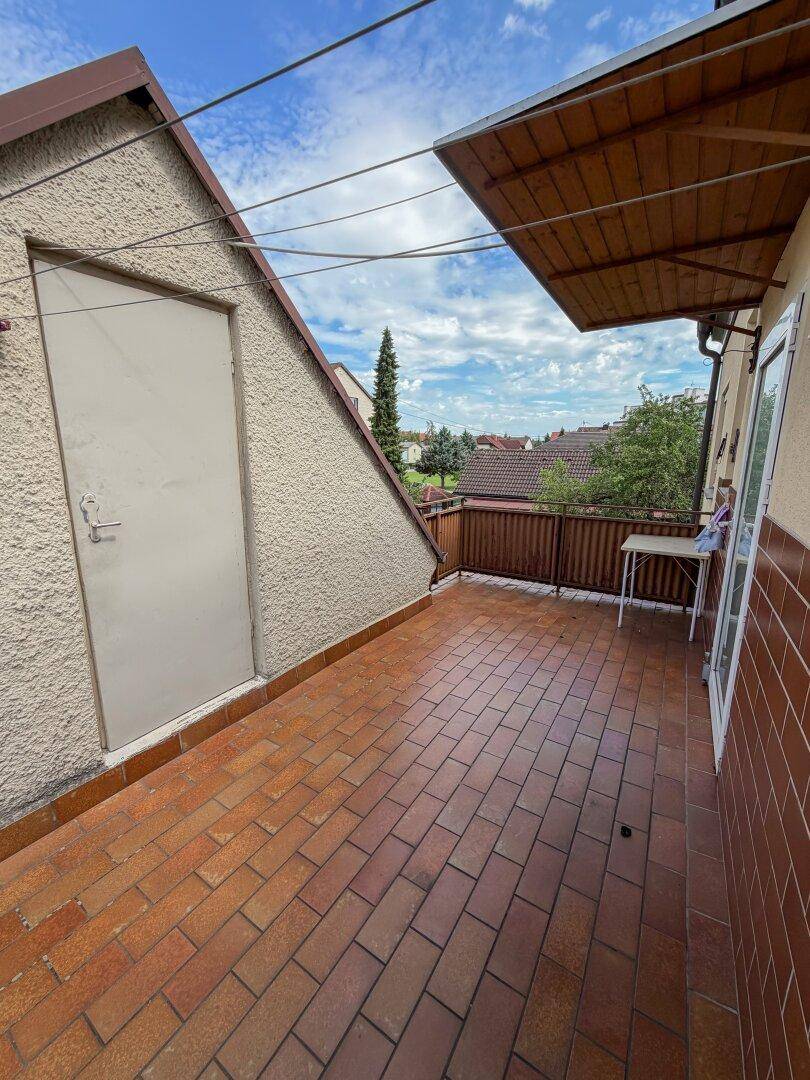 Überdachter Balkon mit Ziegelboden und Blick auf die Umgebung.