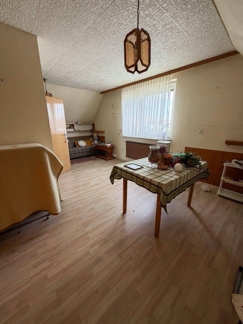 Dachzimmer mit Holzboden, Esstisch und schrägen Wänden.