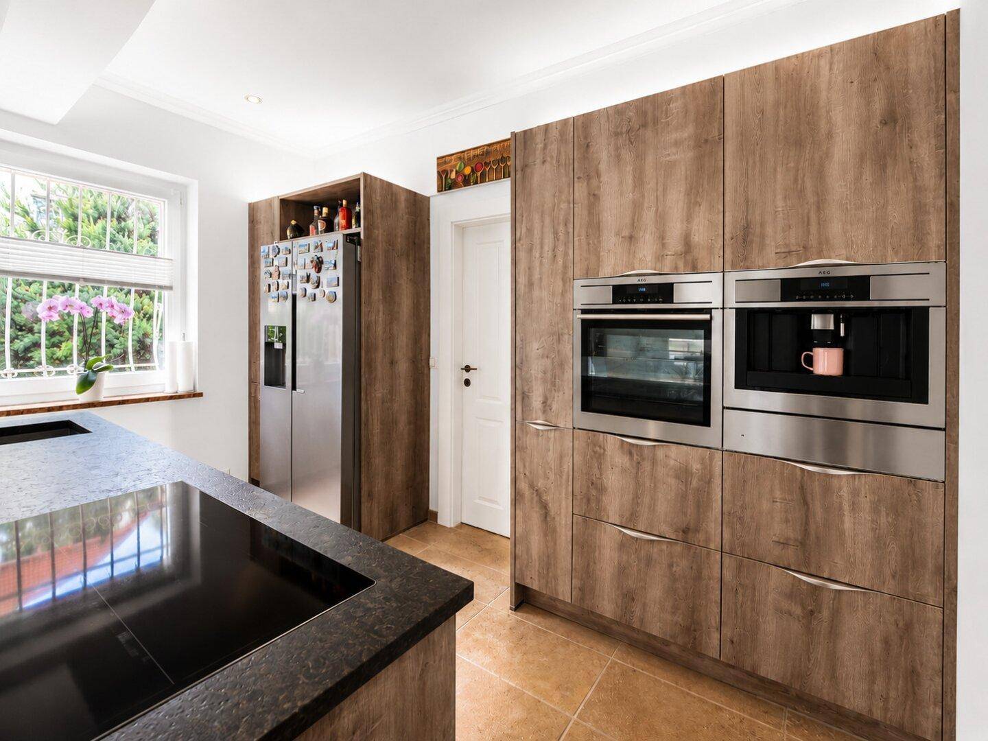 Einbauküche mit modernen Holzfronten, integriertem Backofen und Kaffeemaschine, hell und geräumig.