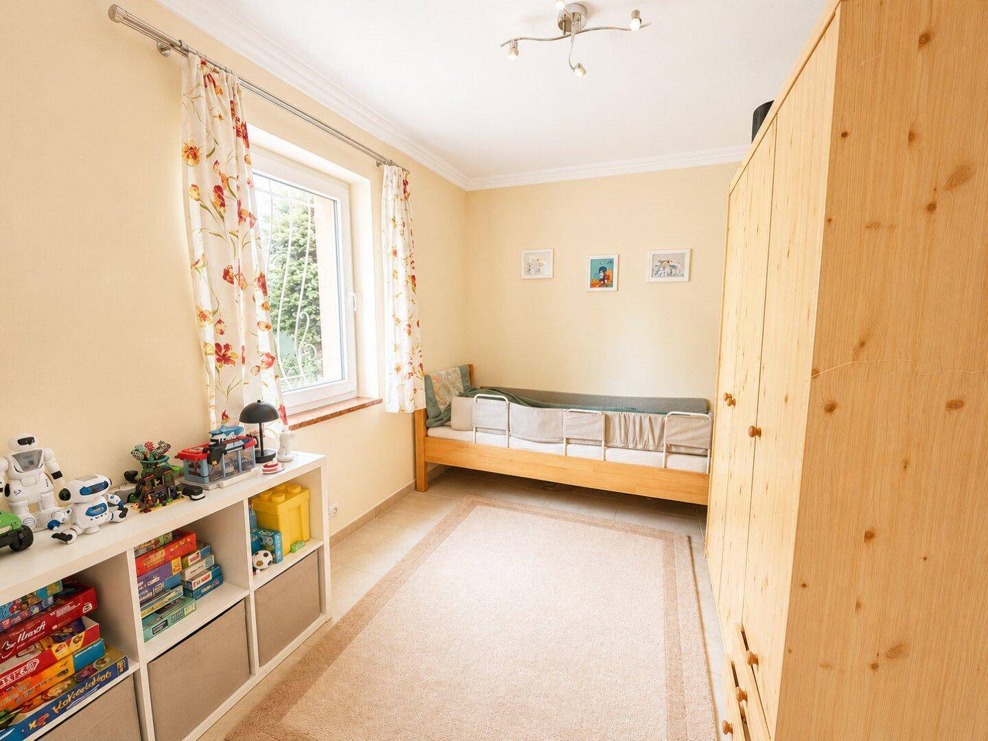 Kinderzimmer mit hellem Fliesenboden, Einzelbett und Holzschrank, freundlich und funktional.