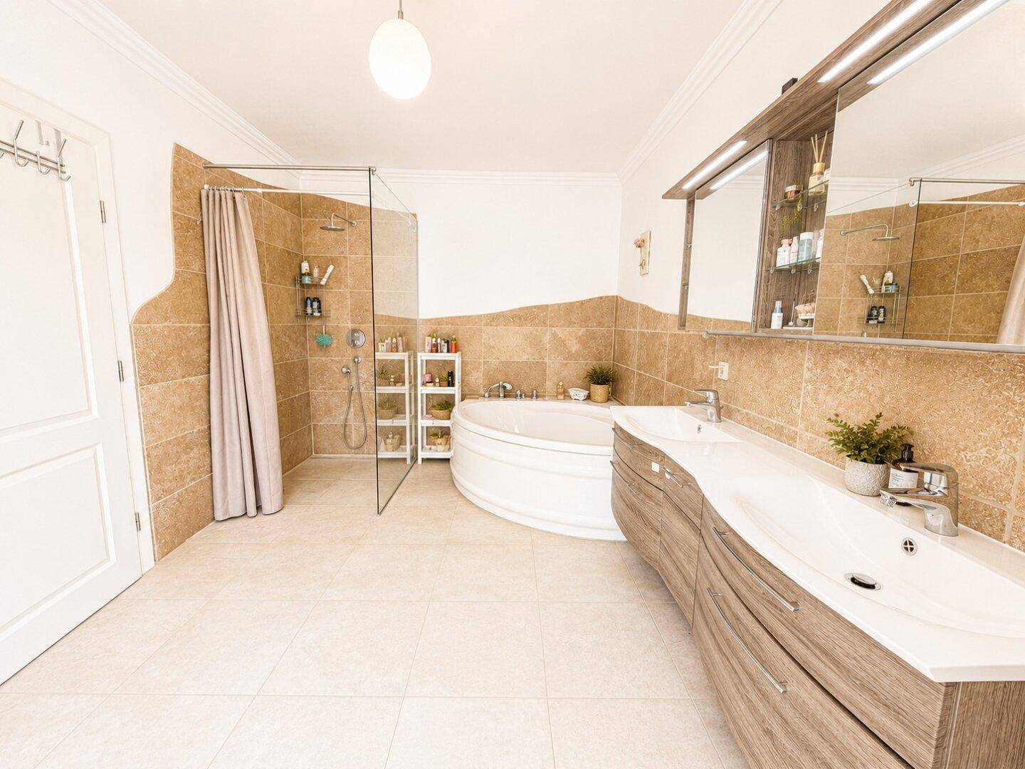 Großes Badezimmer mit Eckbadewanne, begehbarer Dusche und Doppelwaschtisch, luxuriös und geräumig.
