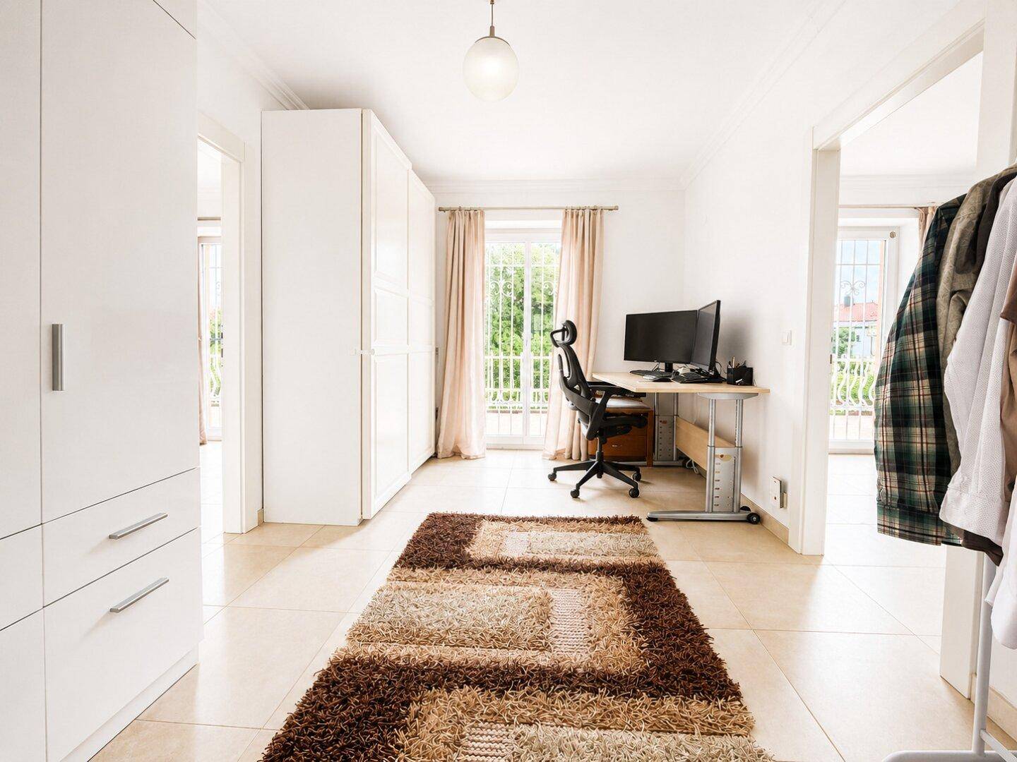 Heller Arbeitsbereich mit Schreibtisch, Bürostuhl und großem Teppich, ideal für Home-Office.