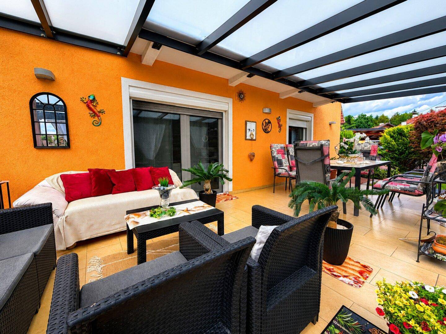 Geräumige überdachte Terrasse mit bequemen Loungemöbeln und Essbereich, perfekt für gesellige Abende.