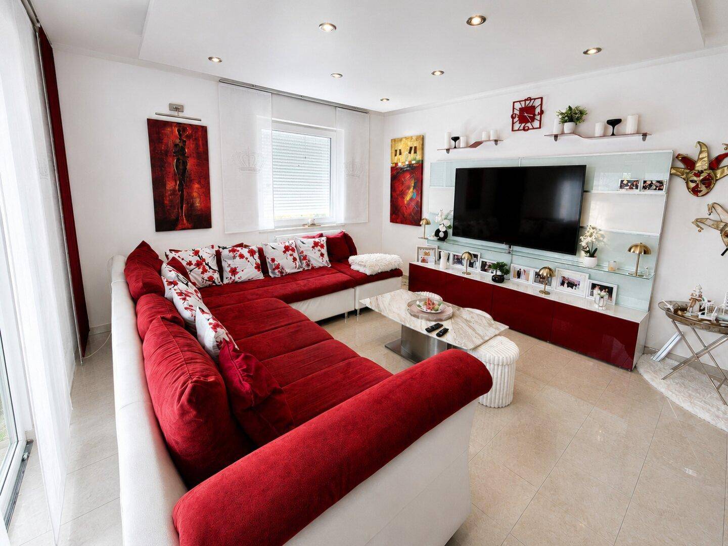 Gemütliches Wohnzimmer mit großer roter Eckcouch, modernem TV-Möbel und stilvoller Dekoration.