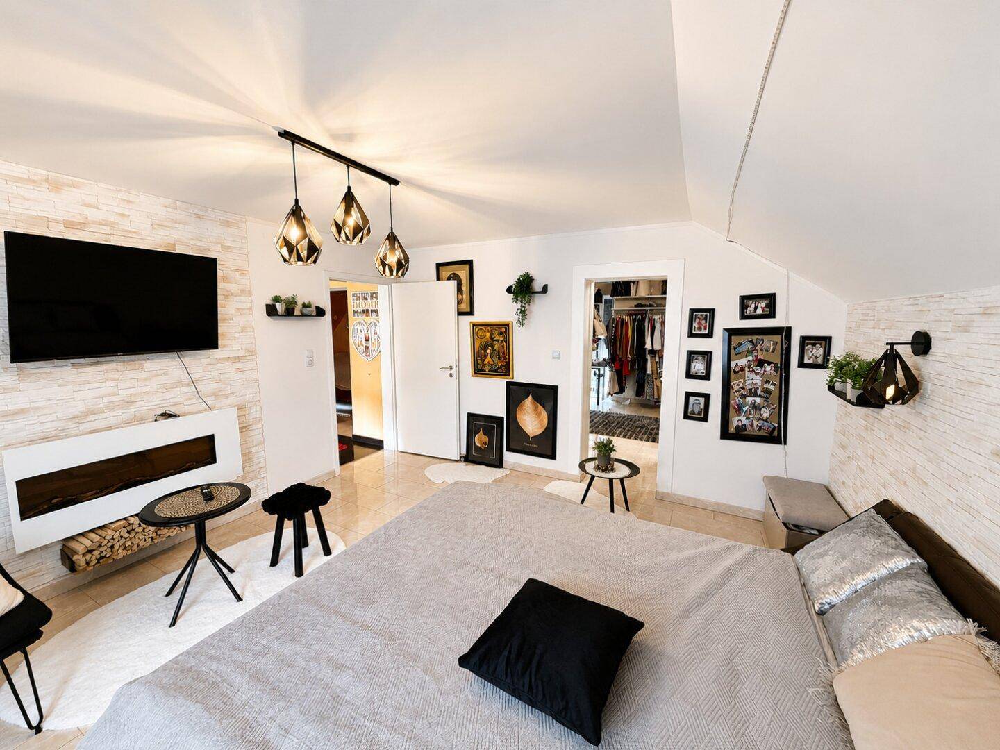 Geräumiges Schlafzimmer im Dachgeschoss mit Doppelbett, TV und dekorativer Steinwand.