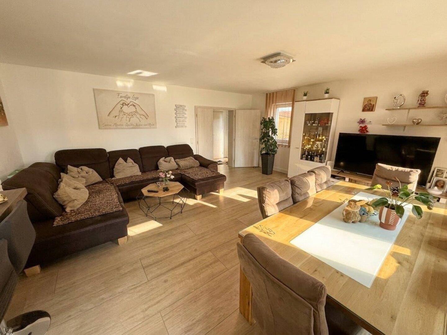 Geräumiger Wohn- und Essbereich mit großem Ecksofa und viel natürlichem Licht.