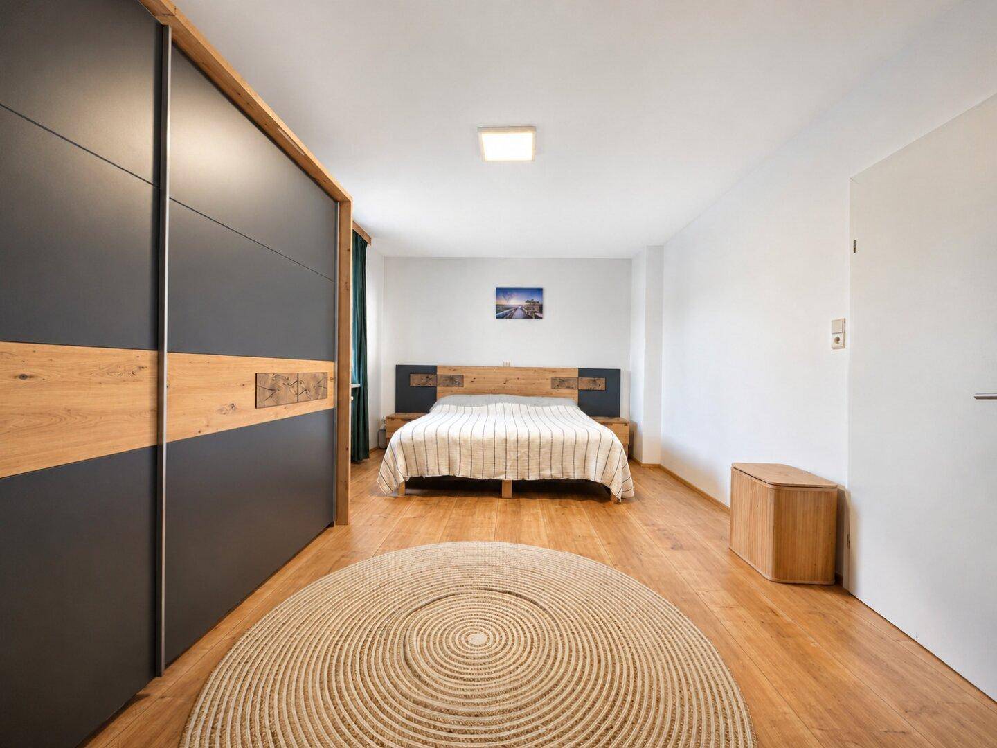 Schlafzimmer mit großem Bett, modernem Einbauschrank und hellem Laminatboden.